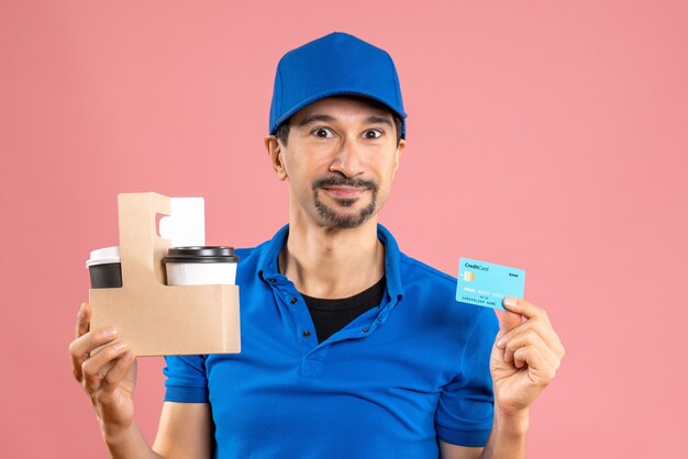 Half body shot of smiling male delivery guy wearing hat holding orders and bank card