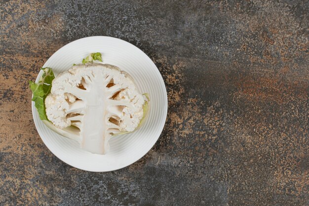 Half cauliflower on the plate, on the marble surface