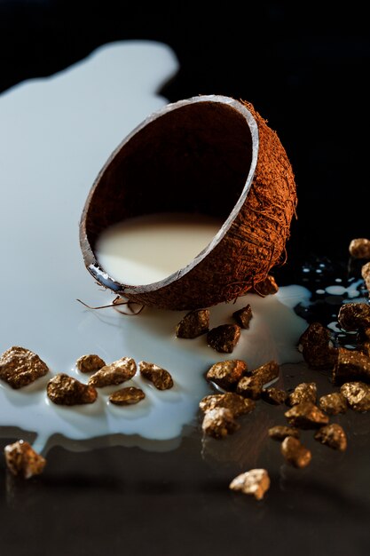 Foto gratuita metà di cocco con latte sulla superficie nera