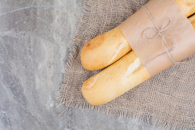 Foto gratuita mezzo taglio di baguette francese su superficie in marmo