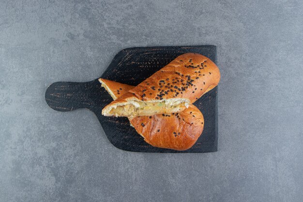 Half-cut fresh pastries with sesame seeds on black board. 