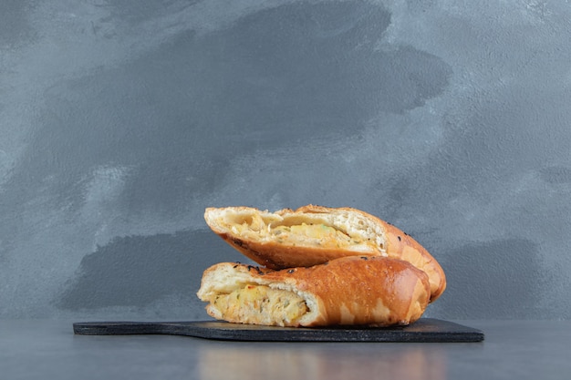 Free photo half-cut fresh pastries with sesame seeds on black board.