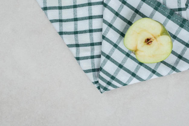 Half cut green apple on striped tablecloth