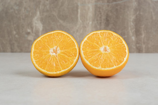 Половина нарезанных сочных апельсинов на сером столе