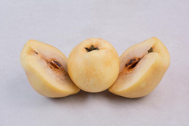 Half cut quince and whole quince on white table.