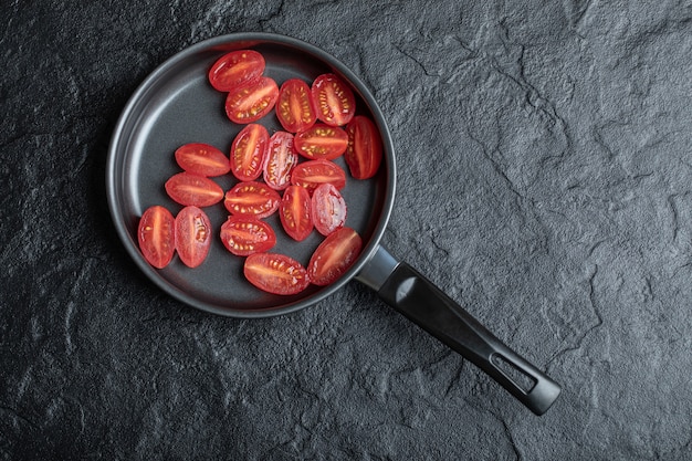 Free photo half cut red cherry tomatoes in frying pan.