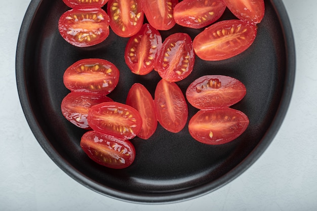 Free photo half cut red cherry tomatoes on frying pan.