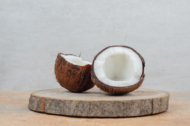 Half cut ripe coconuts on wood piece.