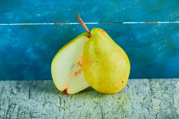 Half cut of ripe pear on blue background.