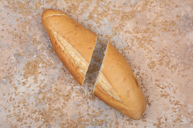 Половина нарезанный пшеничный хлеб с ячменем на мраморной поверхности