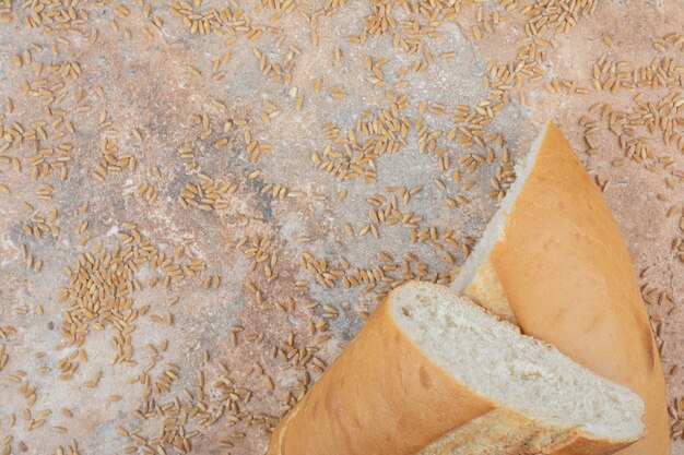 Half cut wheat bread with barley on marble surface