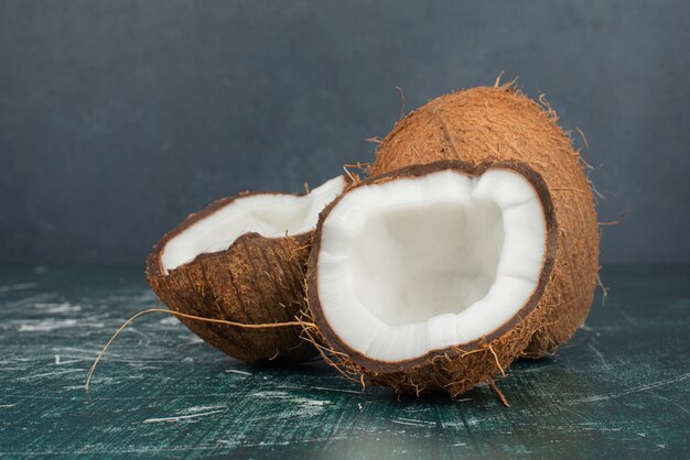 Half cut and whole coconuts on marble table