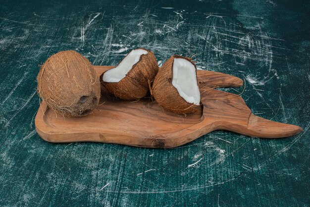 Половина и целые кокосы на деревянной доске.