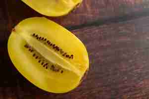 Foto gratuita un kiwi giallo mezzo tagliato su una tavola di legno.