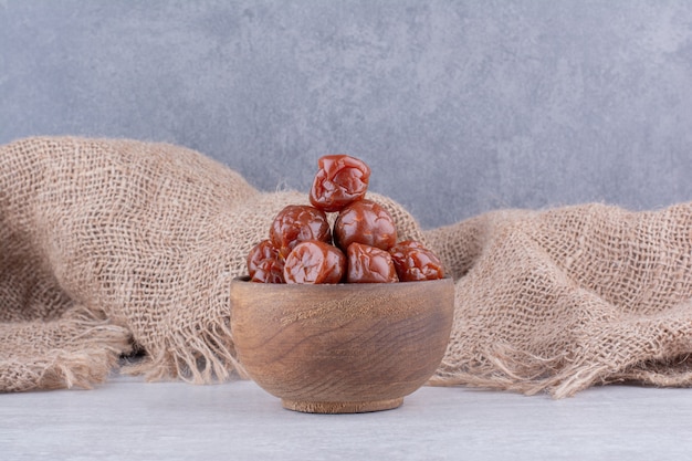 Half dried brown sour cherries in a cup on concrete surface