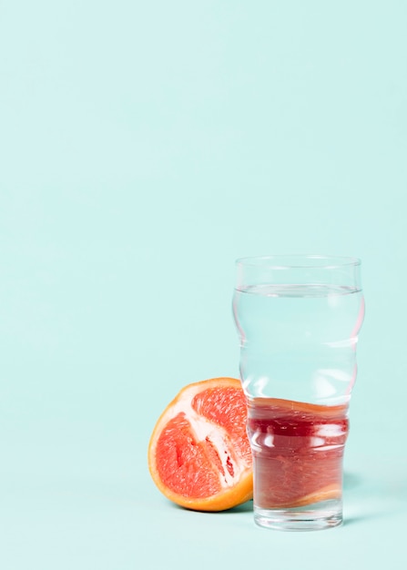 Free photo half of grapefruit with glass of water