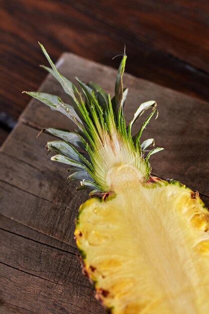 Half a juicy healthy pineapple presented on a kitchen board on a wooden table Ingredient for dessert or salad Top view