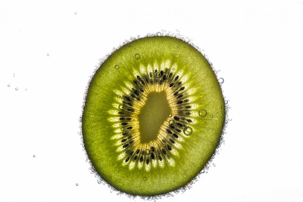 Half of juicy kiwi covered with air bubbles in water