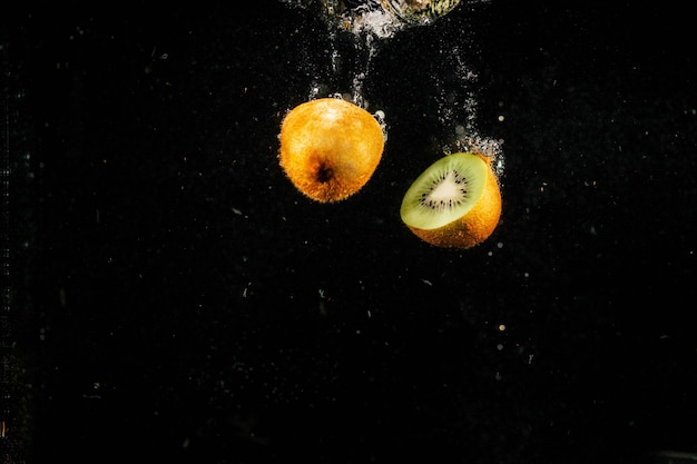 Half of kiwi falling on black background