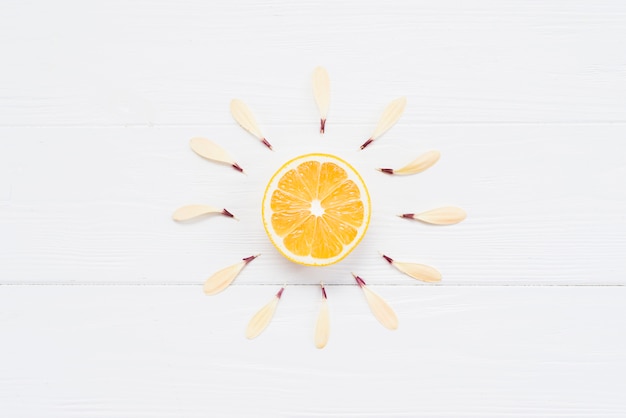 Half of lemon with petals on white background