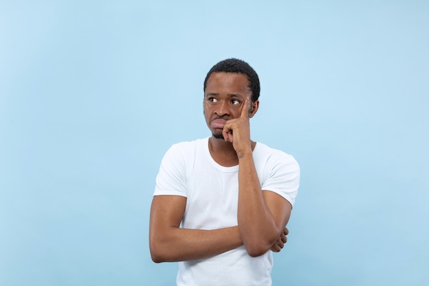 Free photo half-length close up portrait of young african-american man in white shirt on blue space