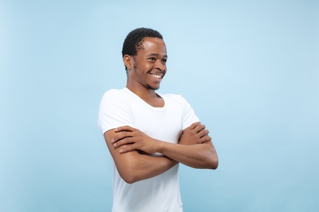 青いスペースに白いシャツを着た若いアフリカ系アメリカ人男性のハーフレングスのクローズアップの肖像画