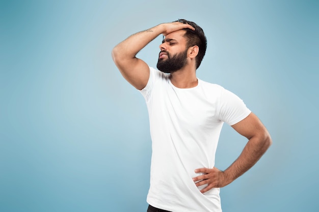 Half-length close up portrait of young hindoo man in white shirt isolated on blue space