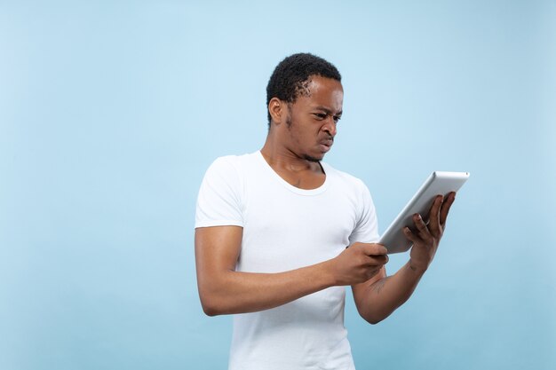 Half-length close up portrait of young man on blue wall