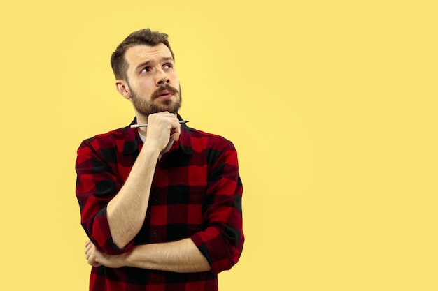 Half-length close up portrait of young man in shirt on yellow space. The human emotions, facial expression concept. Front view. Trendy colors. Negative space