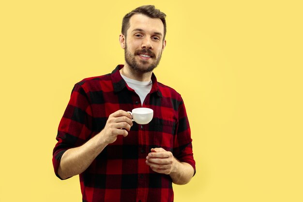 Foto gratuita ritratto alto vicino a mezzo busto di giovane uomo in camicia sullo spazio giallo. le emozioni umane, il concetto di espressione facciale. vista frontale. colori alla moda. spazio negativo