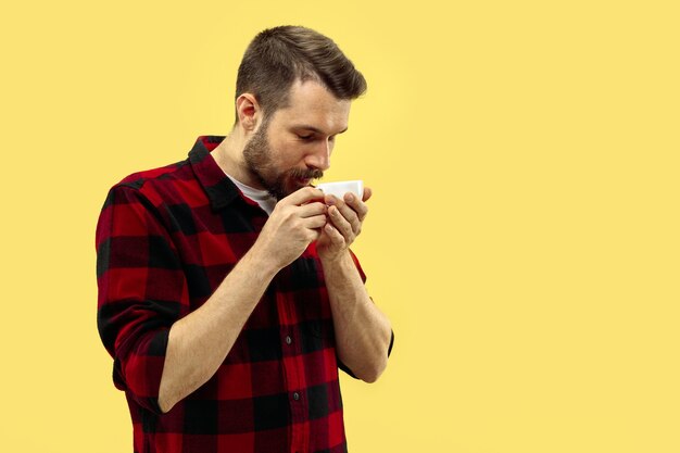 Half-length close up portrait of young man in shirt on yellow space