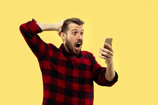 Half-length close up portrait of young man in shirt on yellow space