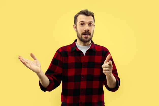 Half-length close up portrait of young man in shirt on yellow