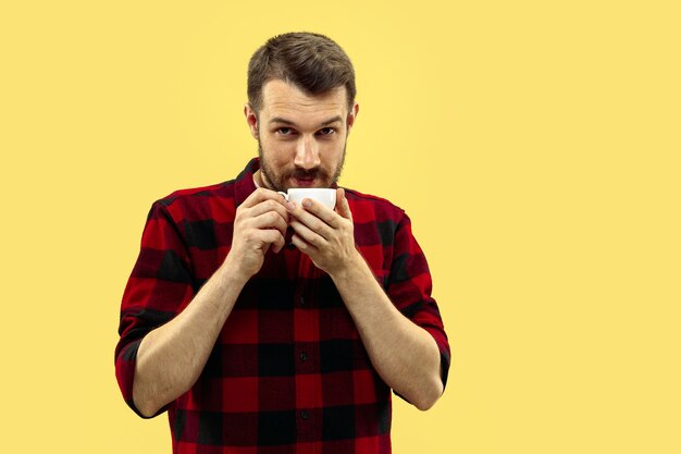 Half-length close up portrait of young man in shirt on yellow