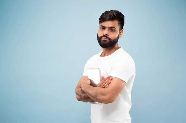 Half-length close up portrait of young man in white shirt on blue