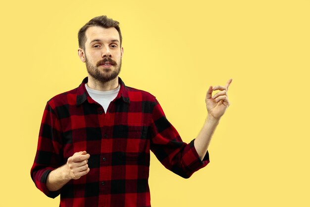 Half-length close up portrait of young man on yellow wall.