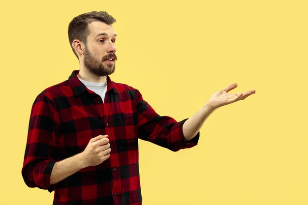 Half-length close up portrait of young man on yellow wall.