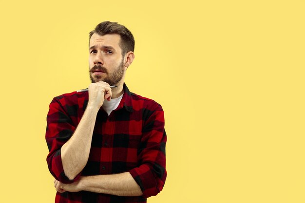 Half-length close up portrait of young man on yellow wall.