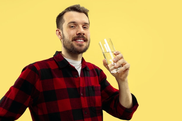 Half-length close up portrait of young man on yellow wall.