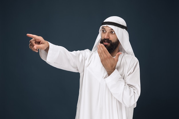 Half-length portrait of arabian saudi businessman on dark blue