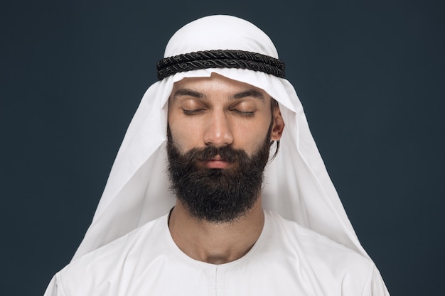 Half-length portrait of arabian saudi businessman on dark blue