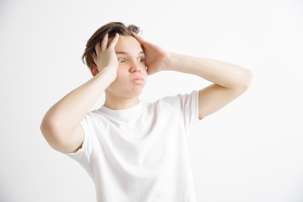 half-length portrait isolated on gray studio backgroud. Young emotional surprised, frustrated and bewildered man. Human emotions, facial expression concept.