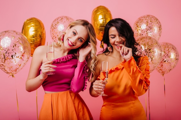 Бесплатное фото Поясной портрет двух девушек, пьющих шампанское