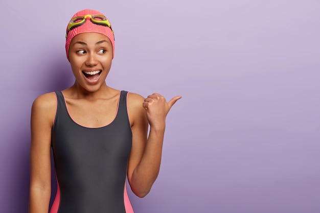 Half length shot of happy swimmer wears swimming goggles, bathingsuit