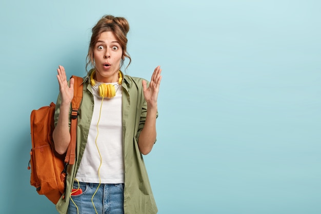 Half length shot of surprised young Caucasian female student makes size gesture, shocked to show something huge