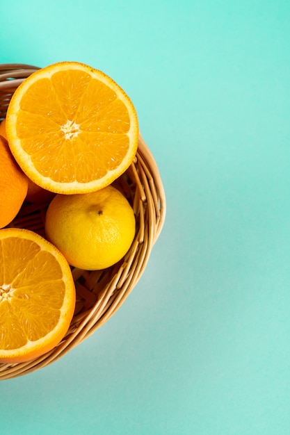 Половина апельсина и лимона в плетеной корзине на столе