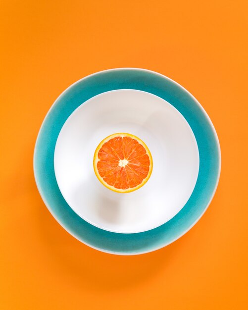 Half orange on a plate. Top view, flat lay