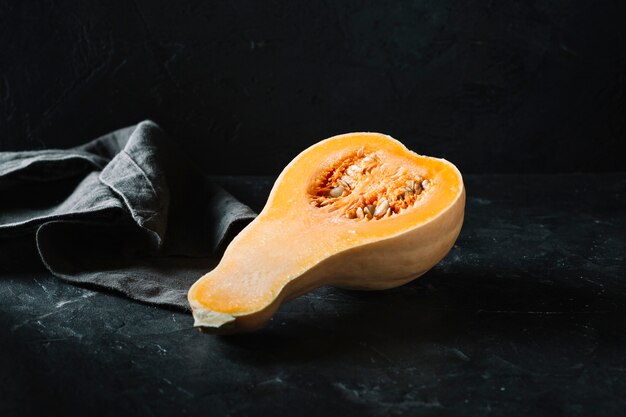 Half of raw organic butternut squash on black background