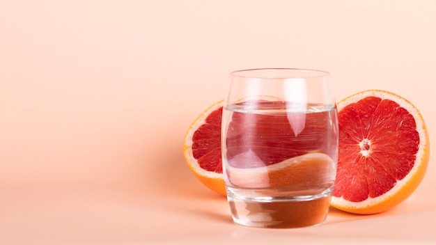 Foto gratuita mezza arancia rossa e vetro sulla disposizione dell'acqua