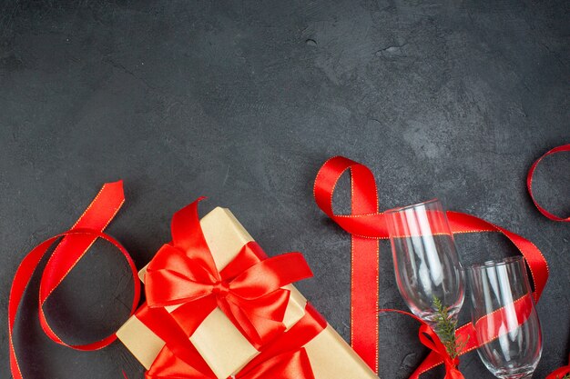 Half shot of beautiful gifts and glass goblets on dark background